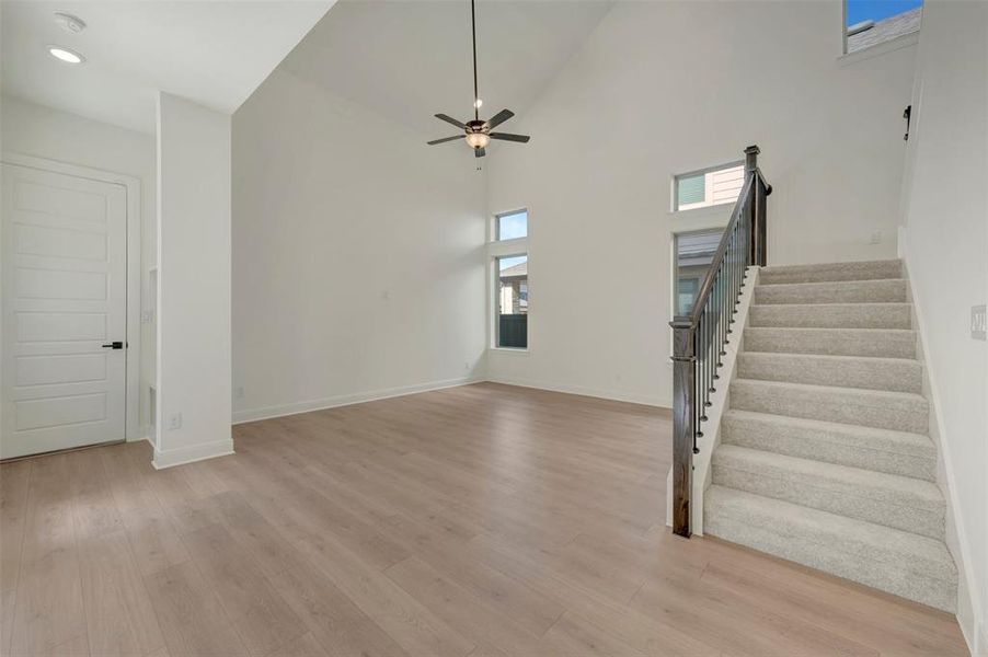 Expansive living area featuring soaring ceilings and wood-finish flooring Expansive living area featuring soaring ceilings and wood-finish flooring