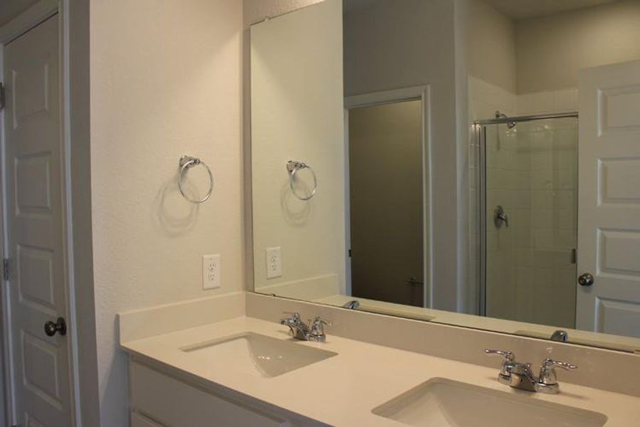 Full bath with a sink, double vanity, and a shower stall