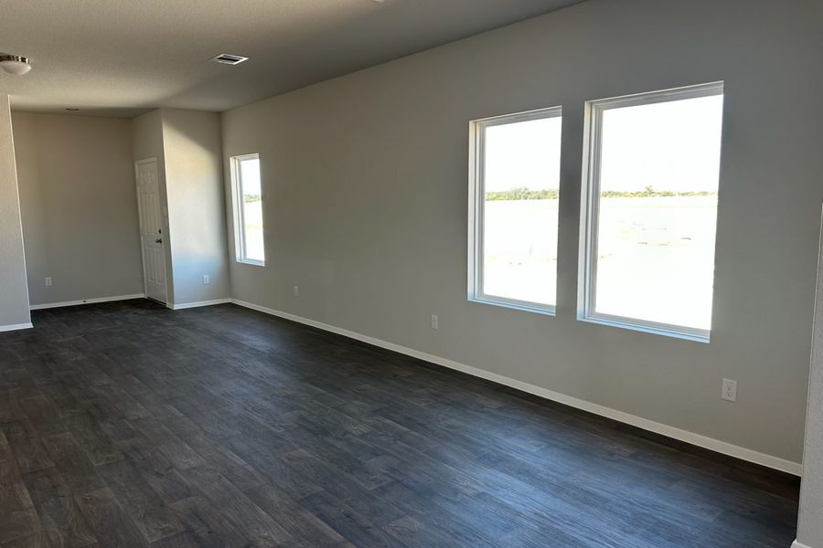 Image of home living room with wood-look floor, white walls, and windows