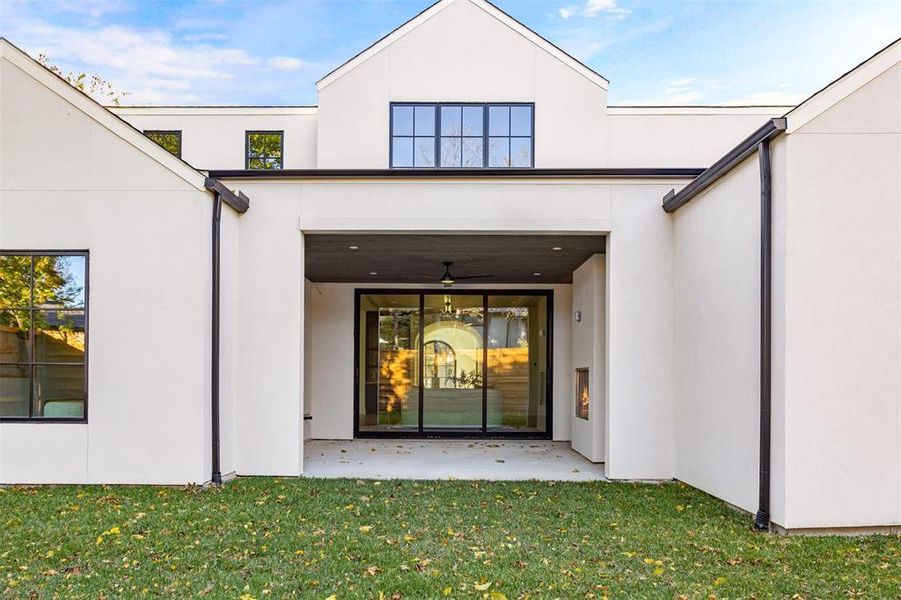Rear view of property with ceiling fan, stucco siding, a patio, and a lawn Rear view of property with ceiling fan, stucco siding, a patio, and a lawn