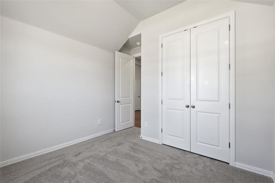 Unfurnished bedroom with carpet flooring, a closet, and vaulted ceiling Unfurnished bedroom with carpet flooring, a closet, and vaulted ceiling