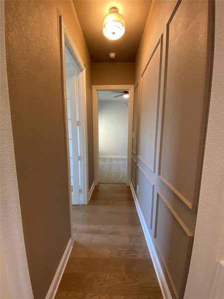 Hallway featuring a textured wall and light wood-style floors Hallway featuring a textured wall and light wood-style floors