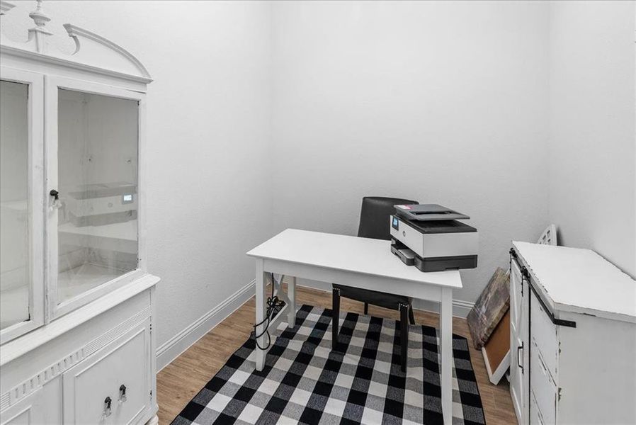 Office area with baseboards and light wood-style flooring