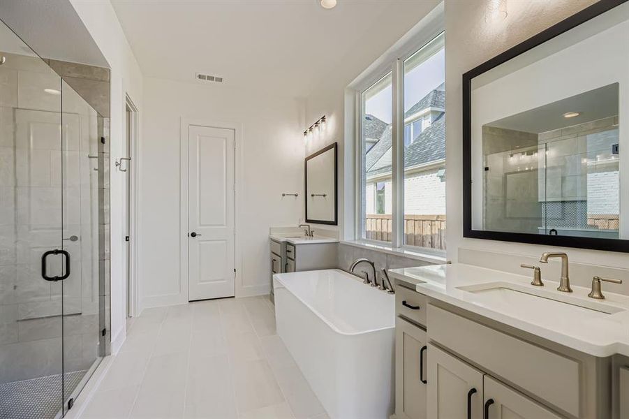 Bathroom with a stall shower, two vanities, a freestanding bath, and recessed lighting