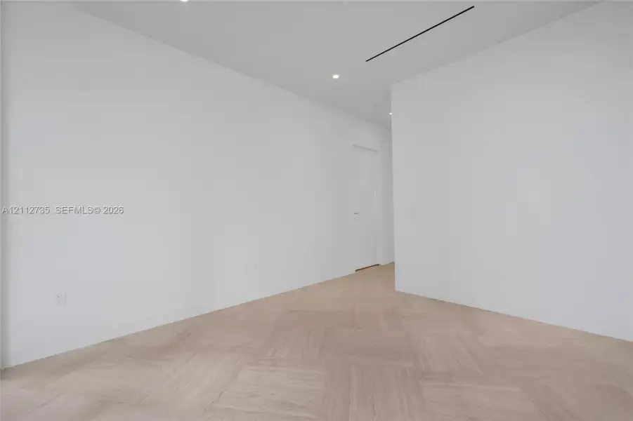 Neutral interior space featuring herringbone wood-finish flooring, recessed lighting, and crisp white wall finishes