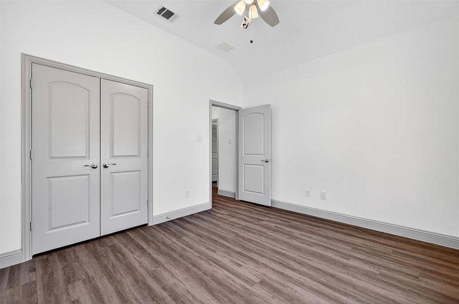Unfurnished bedroom featuring vaulted ceiling, wood finished floors, a ceiling fan, and a closet