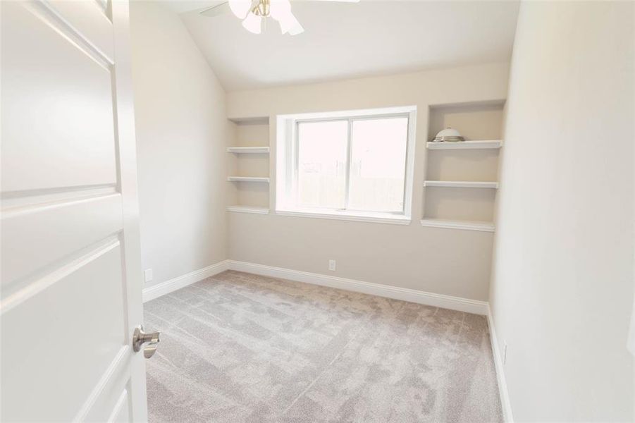 Carpeted spare room featuring lofted ceiling and ceiling fan