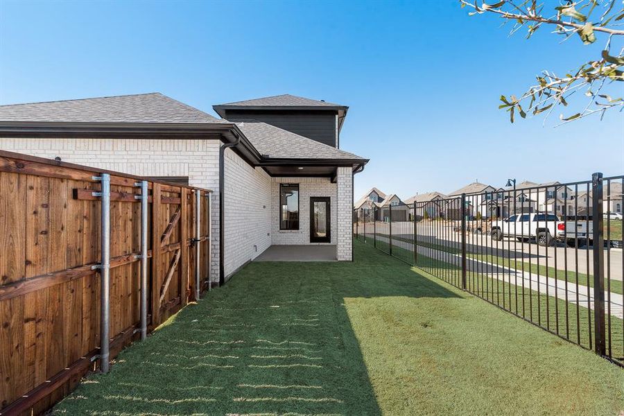 Rear view of house with a shingled roof, a patio area, brick siding, a fenced backyard, and a residential view Rear view of house with a shingled roof, a patio area, brick siding, a fenced backyard, and a residential view