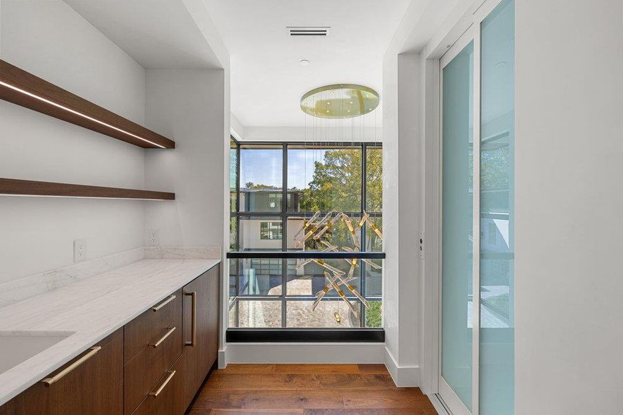 Bar with open shelves, dark wood finished floors, light stone counters, modern cabinets, and dark brown cabinetry