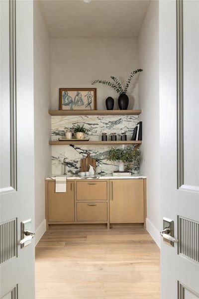 The primary suite, accessed through custom double reeded design doors includes a wet bar vestibule with sink and mini-fridge—ideal for morning coffee or evening refreshments. The primary suite, accessed through custom double reeded design doors includes a wet bar vestibule with sink and mini-fridge—ideal for morning coffee or evening refreshments.