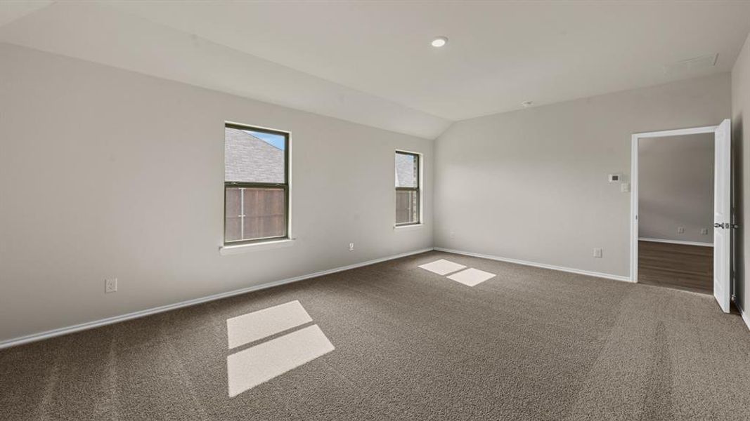 Spacious room featuring vaulted ceilings, recessed lighting, neutral wall tones, and dark carpeting Spacious room featuring vaulted ceilings, recessed lighting, neutral wall tones, and dark carpeting