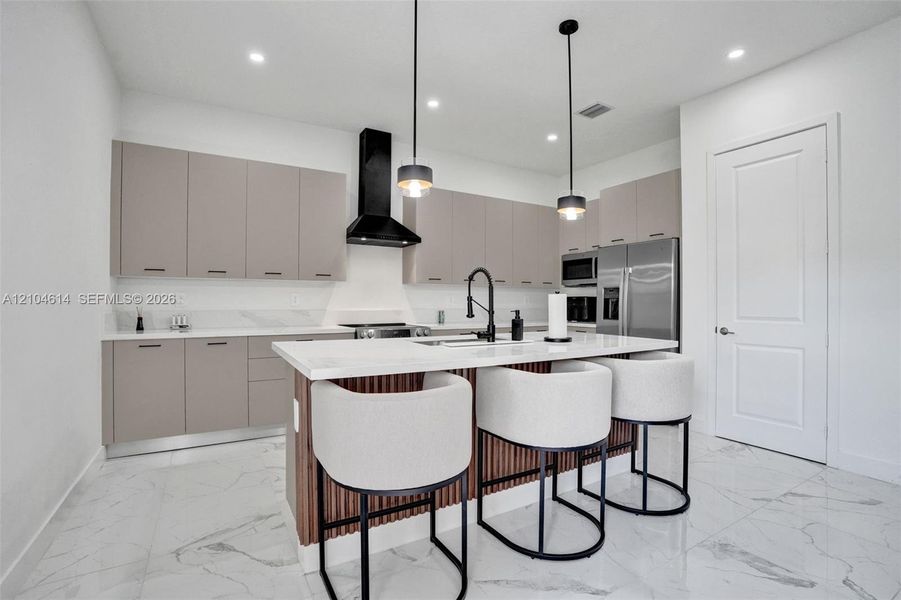 Kitchen featuring an island with white countertop, matte black faucet, and pendant lighting