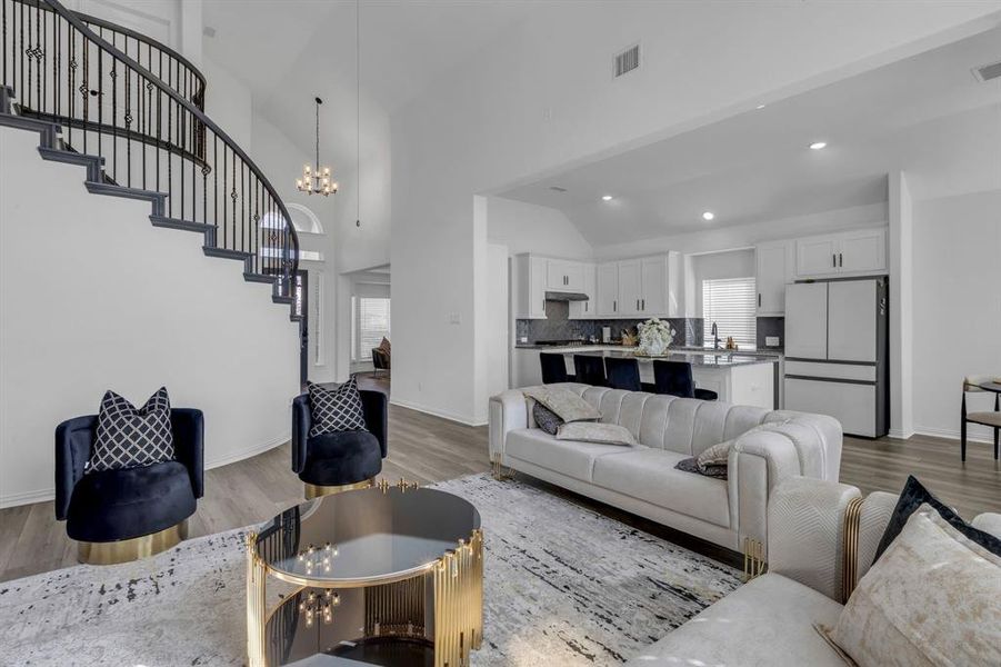 Living room with high vaulted ceiling, light hardwood / wood-style floors, and a chandelier