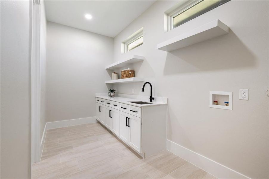 Clothes washing area with hookup for a washing machine, cabinets, and sink