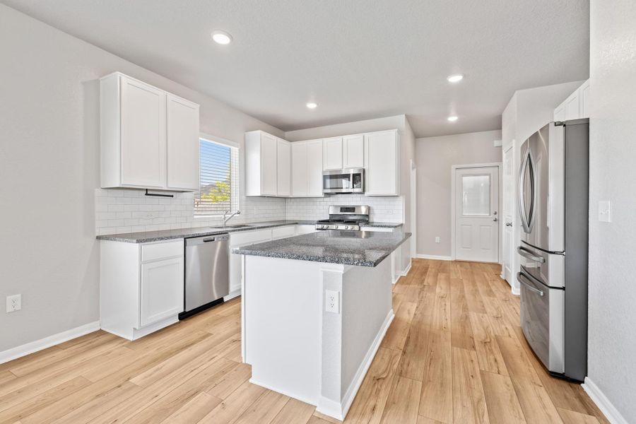 Kitchen with stainless steel appliances, decorative backsplash, white cabinetry, and recessed lighting Kitchen with stainless steel appliances, decorative backsplash, white cabinetry, and recessed lighting