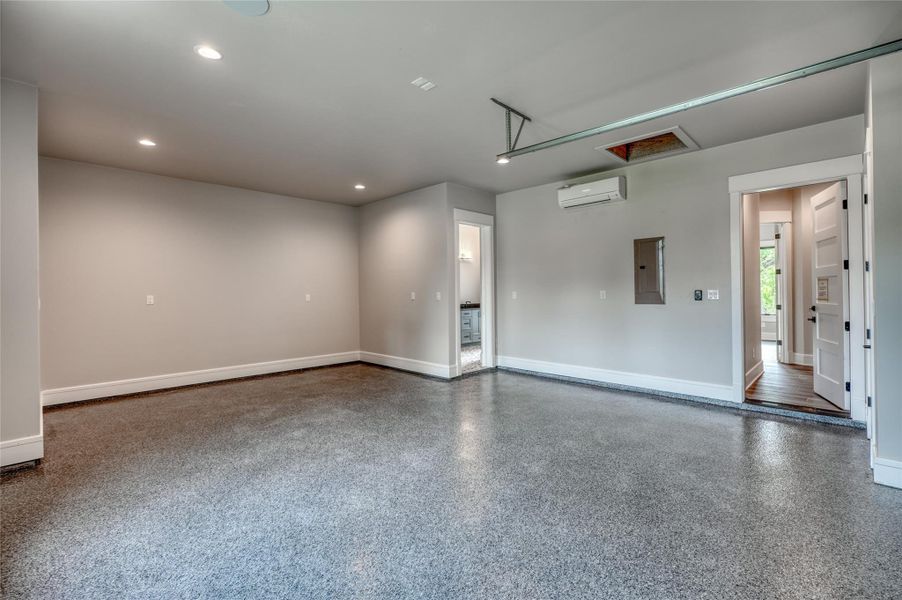 Unfurnished room with an AC wall unit, baseboards, electric panel, recessed lighting, and speckled floor