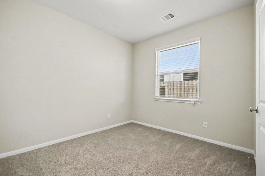 3rd bedroom with neutral walls, soft carpeting, and a large window offering plenty of natural light.