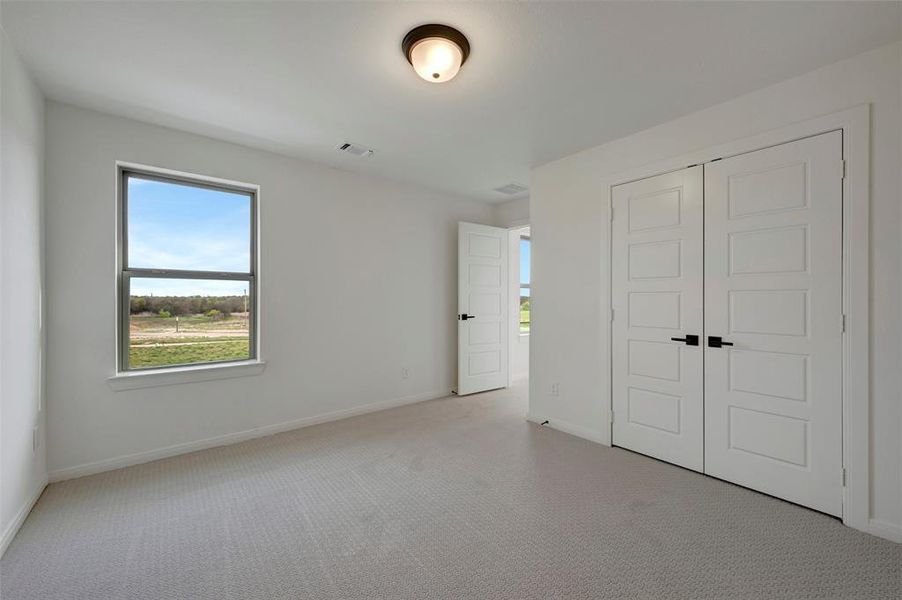 Unfurnished bedroom with light carpet and a closet