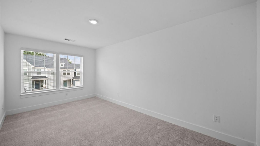 Highly functional bedroom with large windows, carpeted flooring, and tasteful finishes throughout