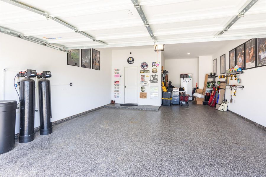 Spacious 3 car garage tandem with epoxy flooring, ample storage space and showing the whole home water softener and filtration system.