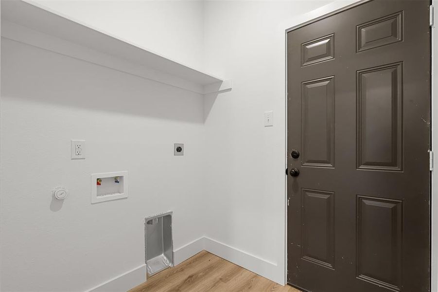 Clothes washing area with electric dryer hookup, hookup for a washing machine, and light hardwood / wood-style flooring