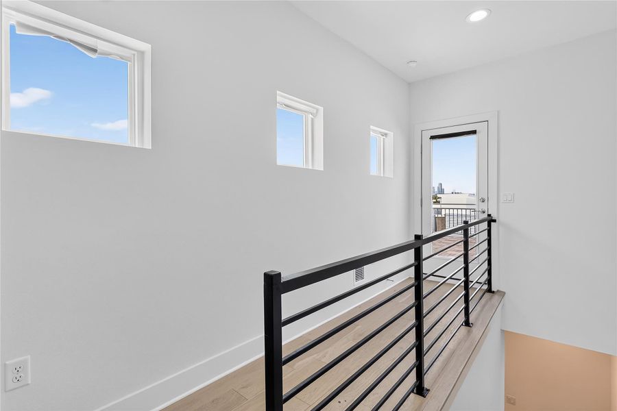 A well-lit upper landing connects to an outdoor balcony with city views.