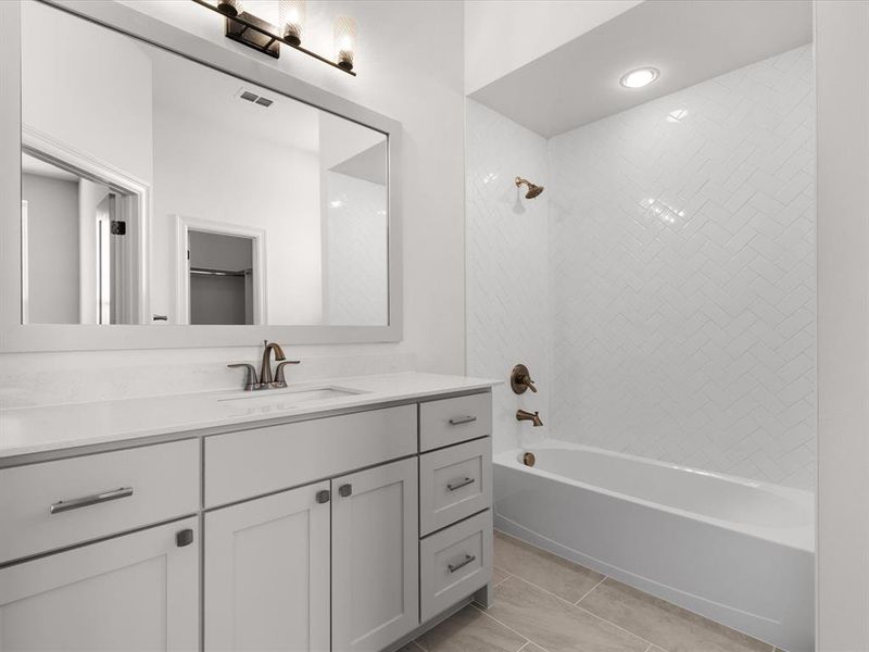 Bathroom featuring washtub / shower combination, vanity, and light tile patterned floors