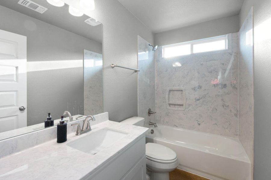 Refined primary bath presents a large vanity, contemporary fixtures, and a clean tub and shower combination.