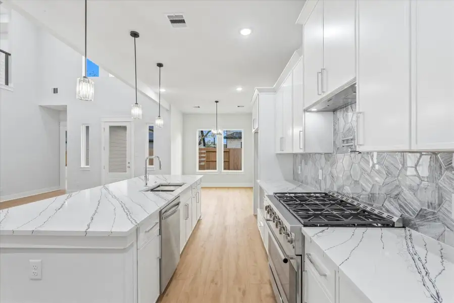 The spacious 10 foot island features an under-mount sink and built in dishwasher. Three pendant lights above add warmth and modern charm.