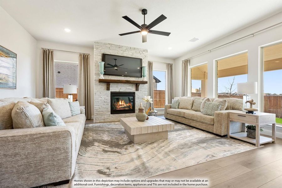 Living room with stone fireplace, ceiling fan, two sofas, and hardwood floors with large windows Living room with stone fireplace, ceiling fan, two sofas, and hardwood floors with large windows