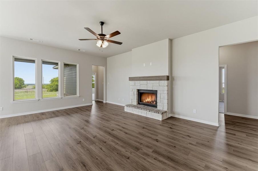 Unfurnished living room with ceiling fan, a fireplace, and dark wood finished floors Unfurnished living room with ceiling fan, a fireplace, and dark wood finished floors