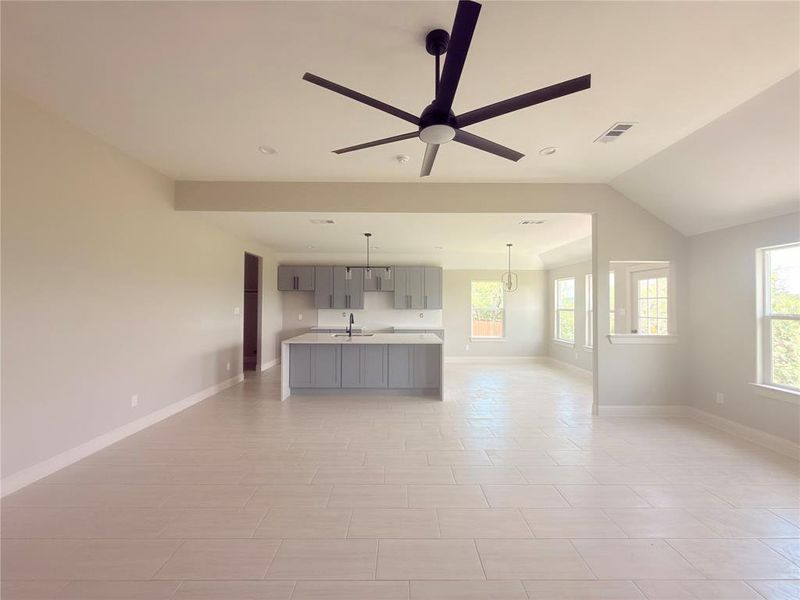 Spacious living area featuring light-toned tile flooring, recessed lighting, and a contemporary ceiling fan
