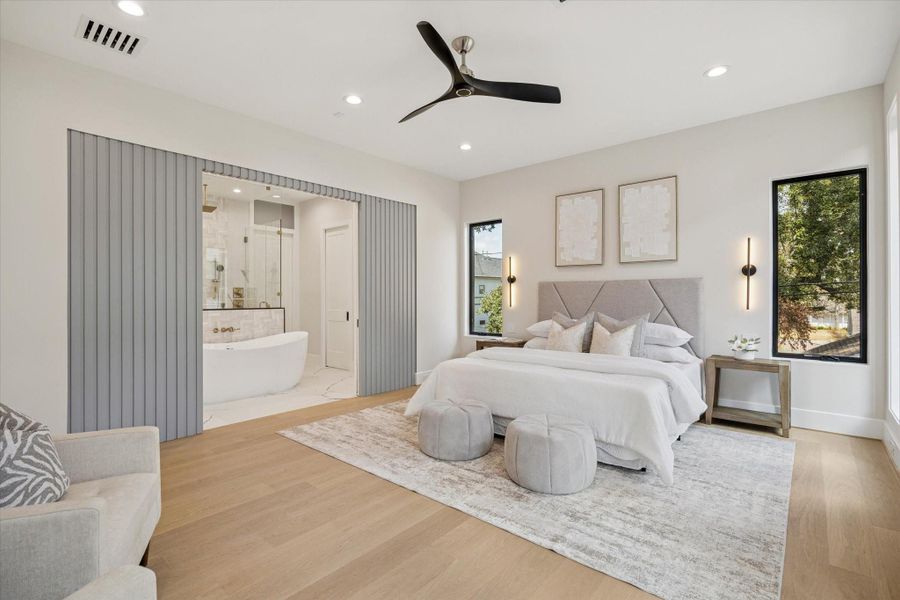 Ascending to the second floor, the primary suite awaits, a sanctuary of indulgence. Outfitted with wood flooring and recessed lighting the room is large enough for a sitting area.