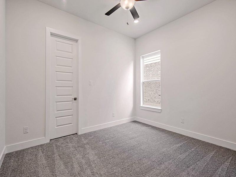 Secondary bedroom with carpet flooring and ceiling fan.