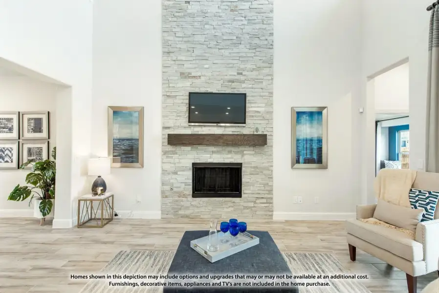 Living room with floor-to-ceiling stacked stone fireplace, wall-mounted TV, and light wood floors Living room with floor-to-ceiling stacked stone fireplace, wall-mounted TV, and light wood floors