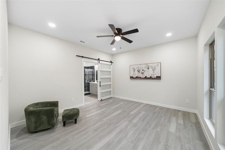 Unfurnished room featuring a barn door, light hardwood / wood-style floors, and ceiling fan