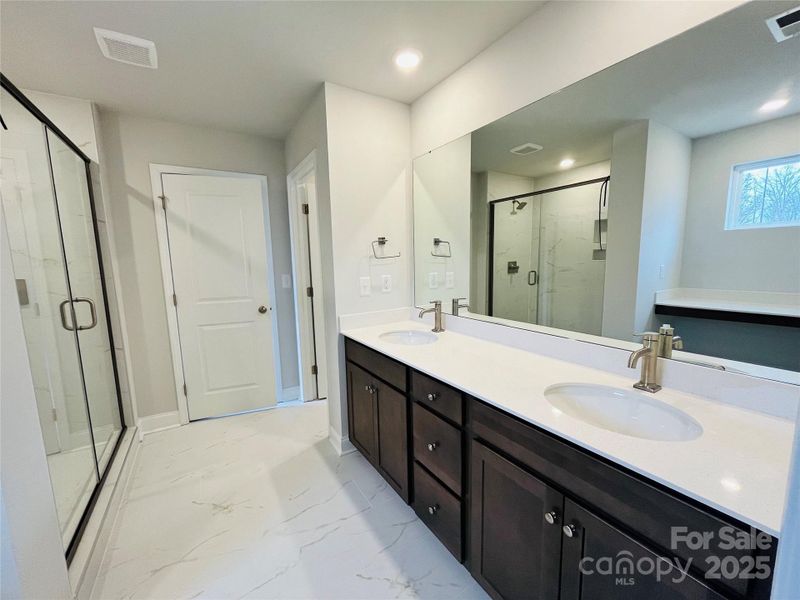 Primary bathroom with tiled shower, quartz counters and walk in closet