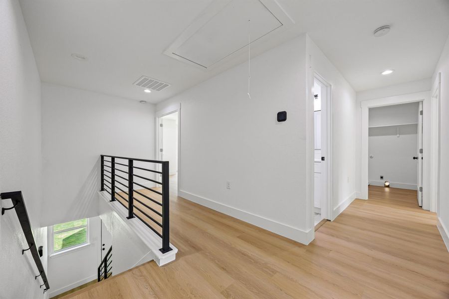 Corridor featuring attic access, an upstairs landing, light wood-style flooring, and recessed lighting Corridor featuring attic access, an upstairs landing, light wood-style flooring, and recessed lighting