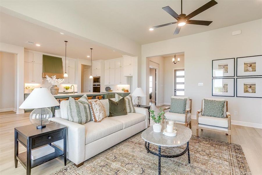 Living room featuring sink, ceiling fan with notable chandelier, and light hardwood / wood-style floors