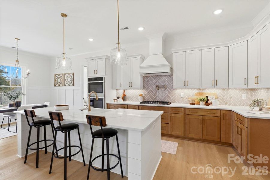 gourmet kitchen- custom  wood hood vent, porcelain farmmhouse sink, high quality quartz island, double oven, gas cooktop