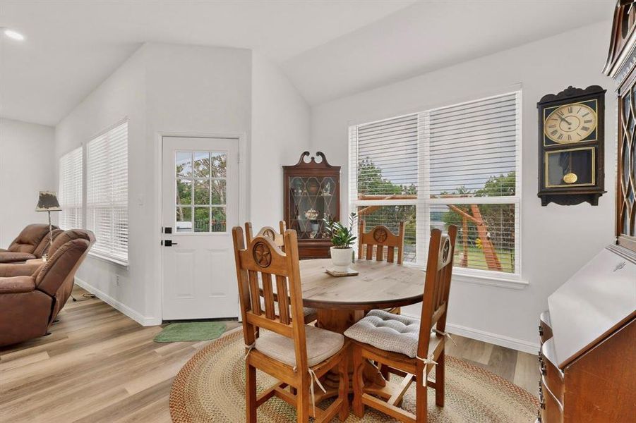 Bright interior space featuring wood-finish flooring, vaulted ceilings, and white walls