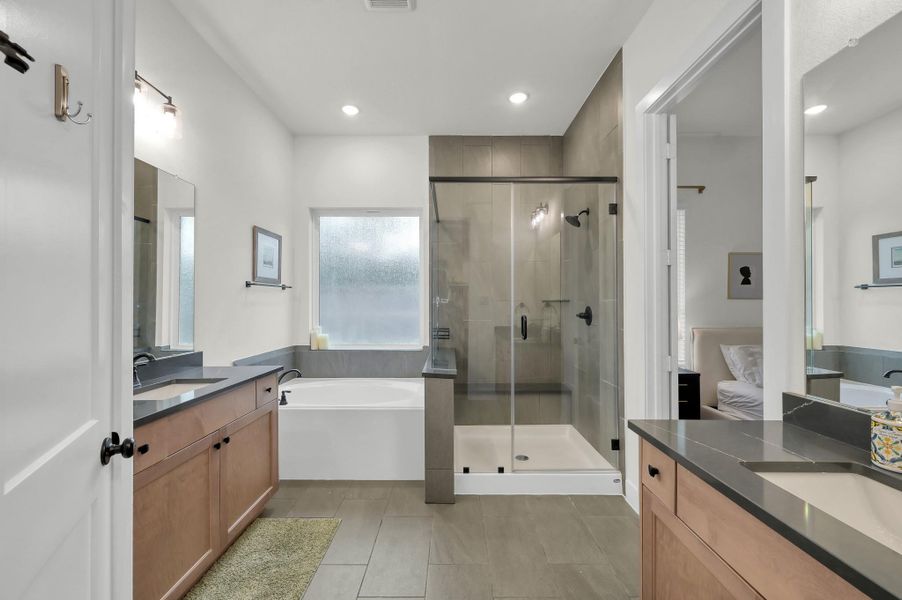 Spa-inspired primary bath with dual vanities, walk-in shower, and a large walk-in closet featuring three rows of hanging space for exceptional wardrobe storage.
