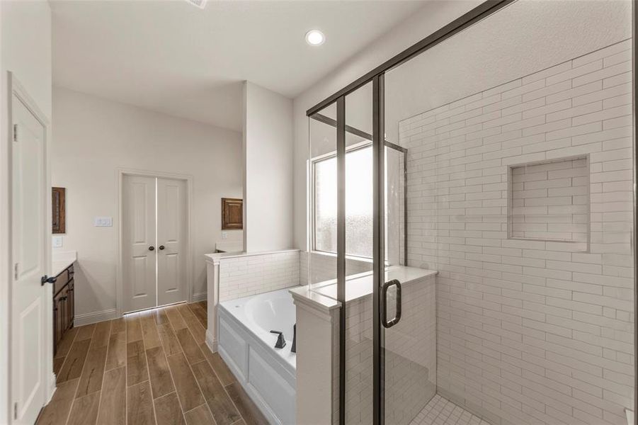 Bathroom with vanity, a bath, a stall shower, wood tiled floors, and recessed lighting Bathroom with vanity, a bath, a stall shower, wood tiled floors, and recessed lighting