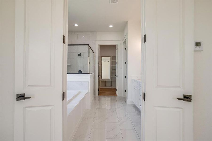 Bathroom with marble finish floors, a shower stall, a garden tub, recessed lighting, and vanity