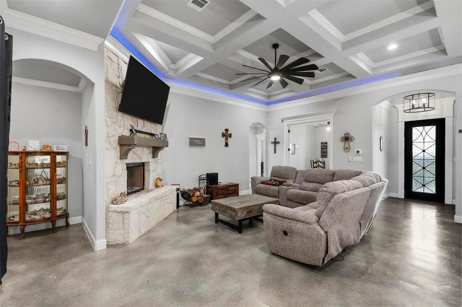 Living room with beamed ceiling, coffered ceiling, crown molding, and concrete floors