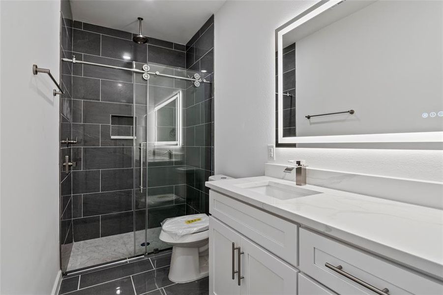 Bathroom featuring tile patterned flooring, vanity, a shower with shower door, and toilet