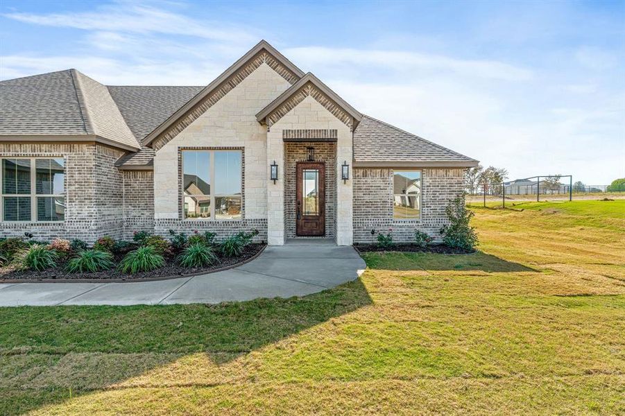 French country style house featuring brick siding, roof with shingles, and stone siding