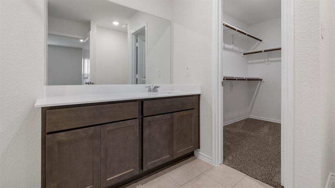 Bathroom with light carpet, vanity, a spacious closet, and light tile patterned flooring