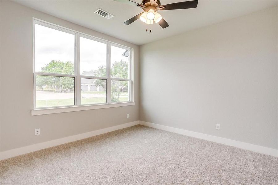 Empty room with ceiling fan, light carpet, visible vents, and baseboards Empty room with ceiling fan, light carpet, visible vents, and baseboards
