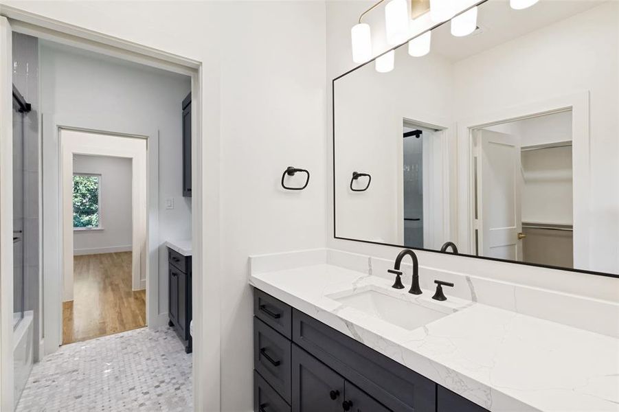 Bathroom featuring a dark wood-finish vanity with white countertop, integrated sink, and matte black fixtures Bathroom featuring a dark wood-finish vanity with white countertop, integrated sink, and matte black fixtures
